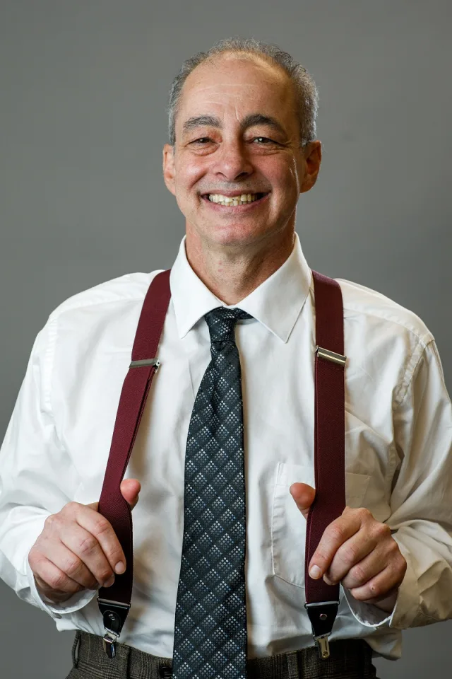 Dr. Joel Chariton smiling in shirt and suspenders